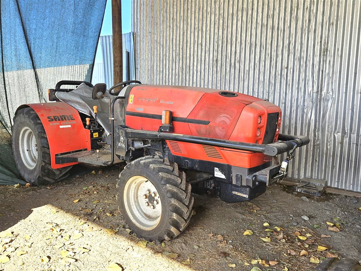 Red SAME low-profile orchard tractor parked in a shed